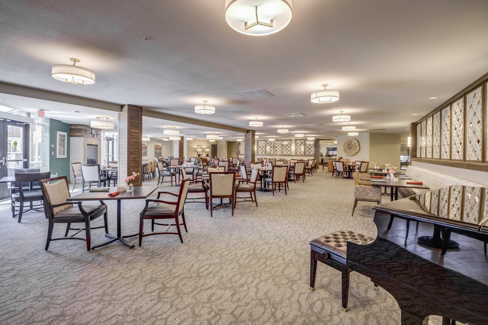 A spacious dining area with neatly arranged tables and chairs, illuminated by modern ceiling lights.