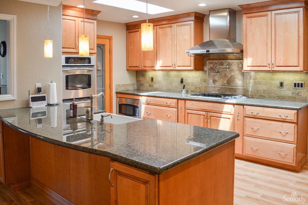A modern kitchen with wood cabinets and a granite countertop island.