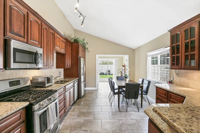 A modern kitchen with stainless steel appliances and a dining area leading to the backyard.
