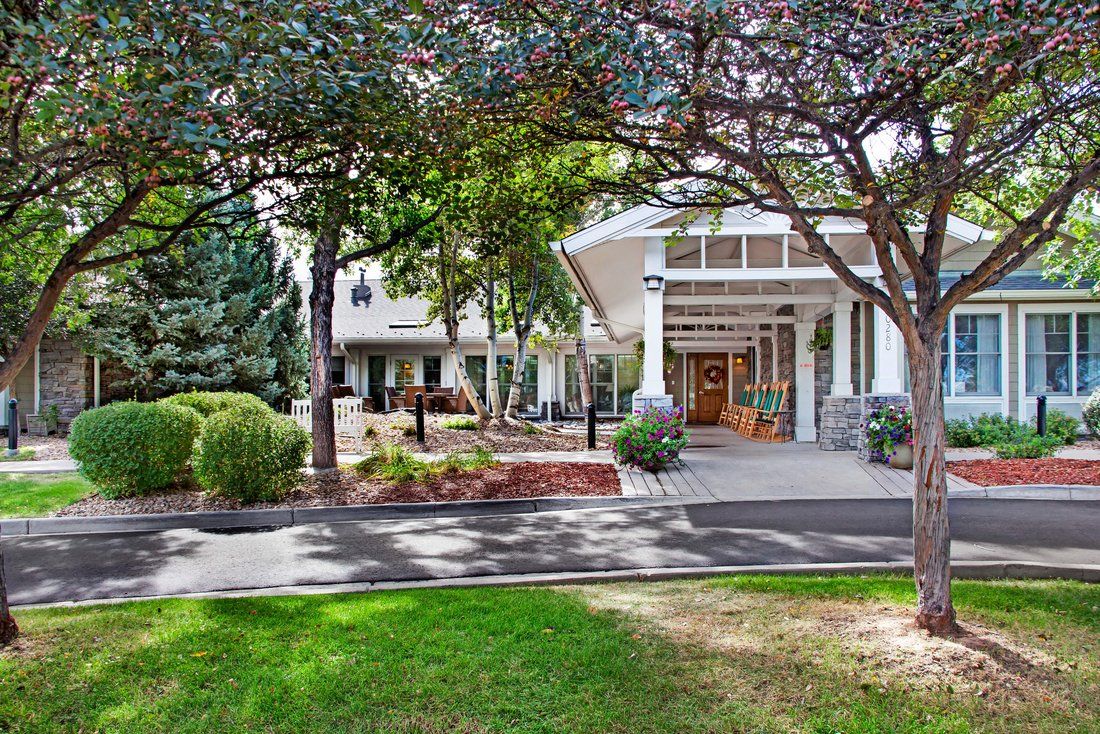 A well-maintained building entrance surrounded by trees and landscaped greenery on a sunny day.