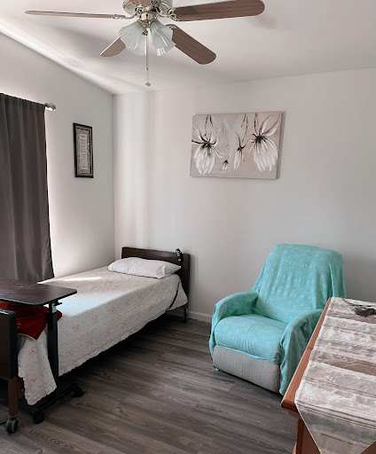 A cozy and minimalistic bedroom setup featuring a single bed, a comfortable chair, and decorative wall art.