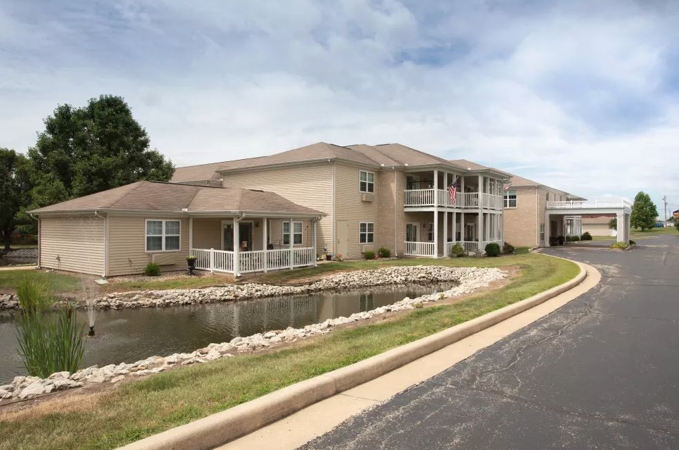 An exterior view of a residential apartment complex with a pond and landscaped surroundings.