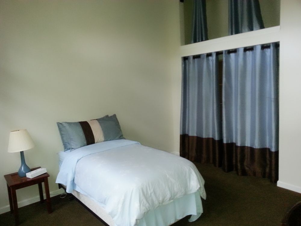A minimalist bedroom featuring a single bed with two pillows and elegant curtains.