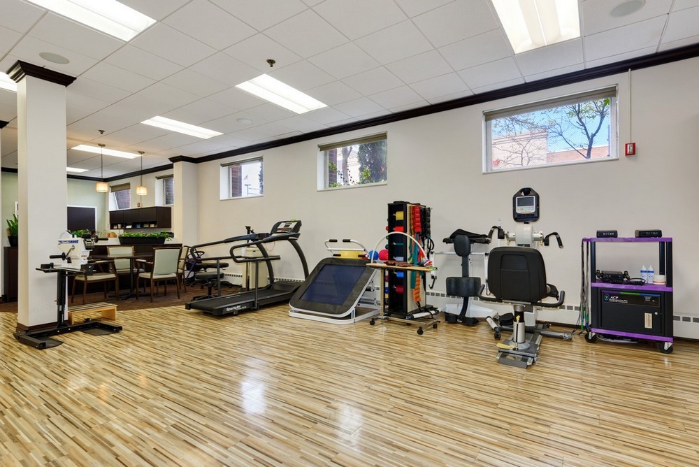 A well-equipped gym with various exercise machines and a wooden floor.