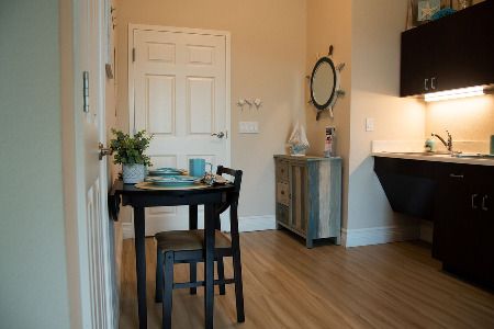 A cozy dining area with a small table set for two, featuring minimalist decor and hardwood flooring.