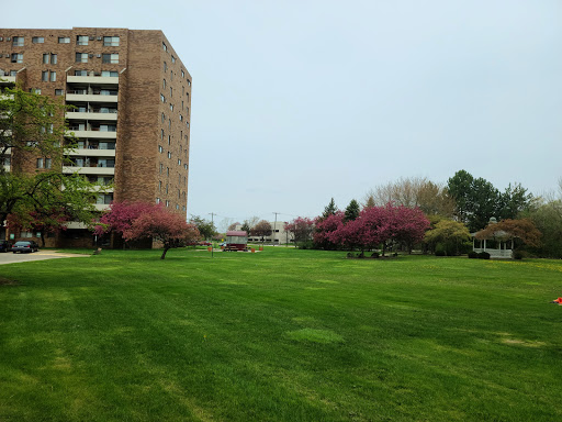 A serene view of an apartment building surrounded by lush green grass and blooming trees.