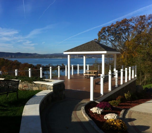 A picturesque waterfront gazebo overlooking a serene lake under a clear blue sky.
