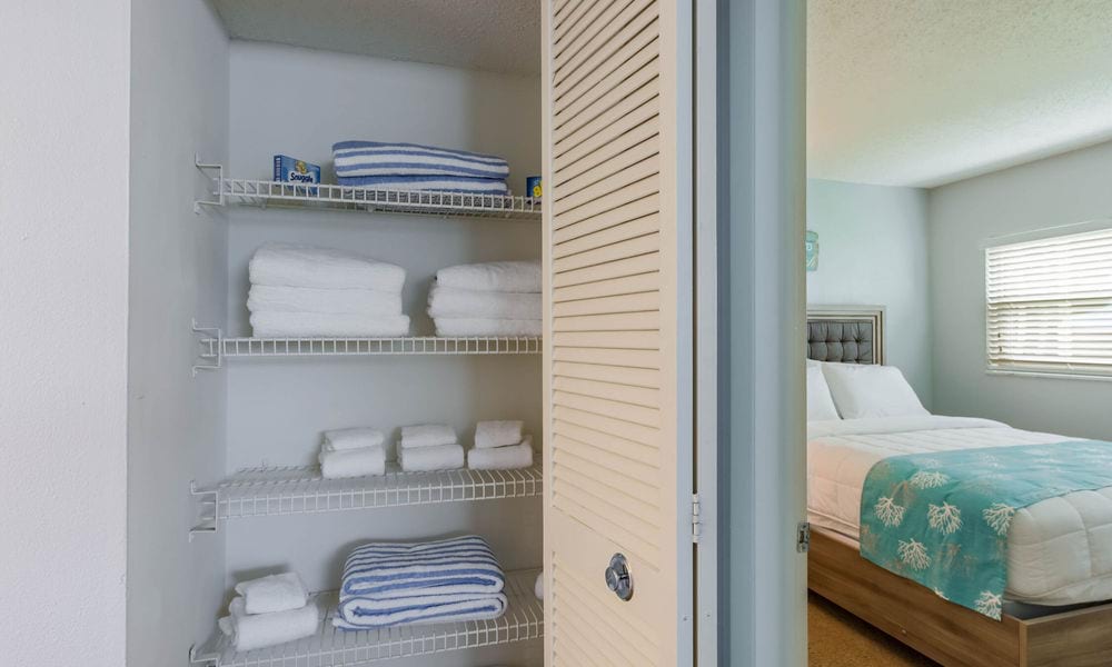 A neatly organized linen closet with folded towels on wire shelves.
