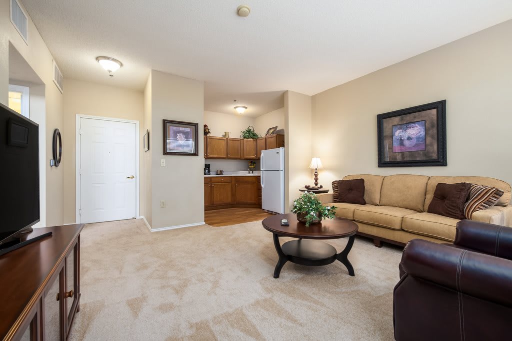 A cozy apartment living room with a sofa, coffee table, and a kitchenette in the background.