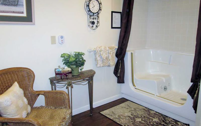 A well-decorated bathroom with a table, plants, and a wall clock.