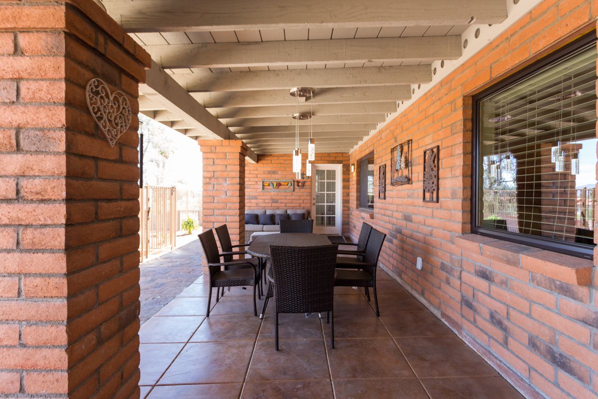 A cozy outdoor patio with a dining set and ceiling fan under a covered area.