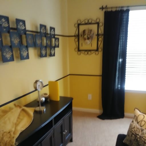 A cozy living room with yellow walls, black curtains, and decorative artwork.