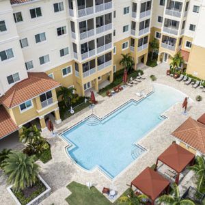 Aerial view of a residential apartment complex with a central swimming pool and surrounding amenities.