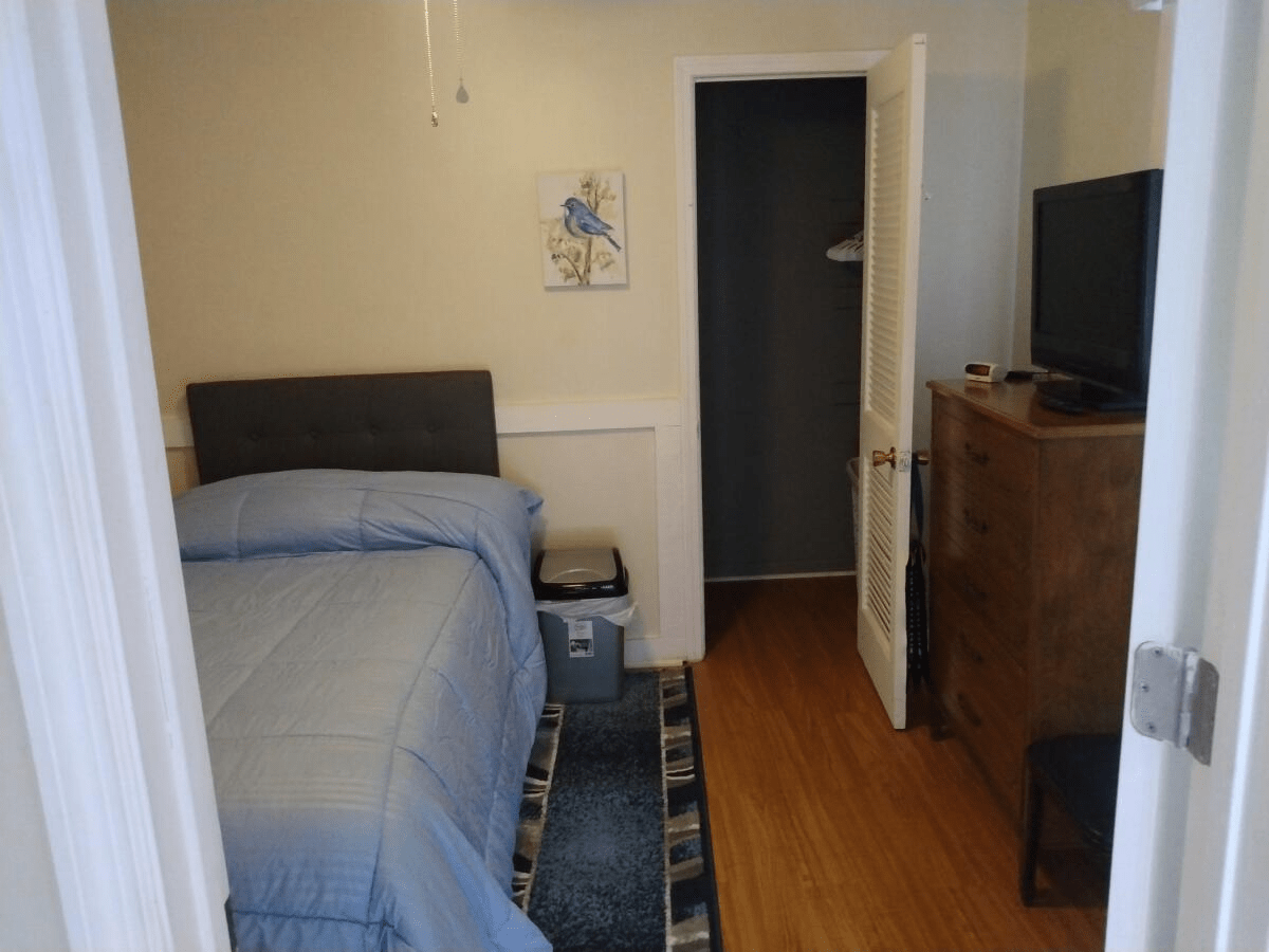 A small bedroom with a bed, dresser, and television.