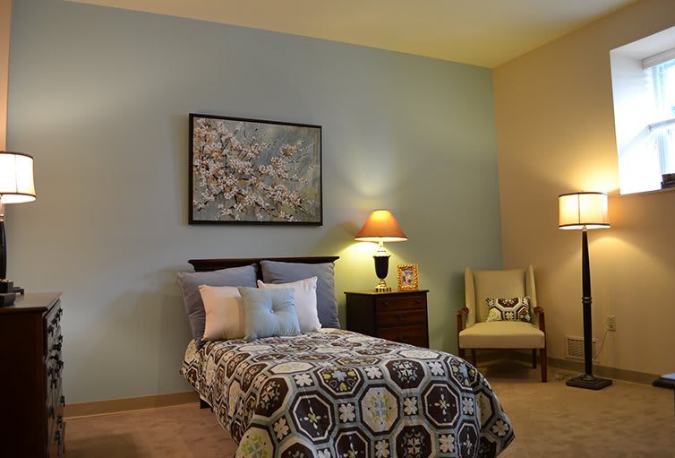 A cozy bedroom with a neatly made bed, artistic wall decor, and soft lighting from table lamps.