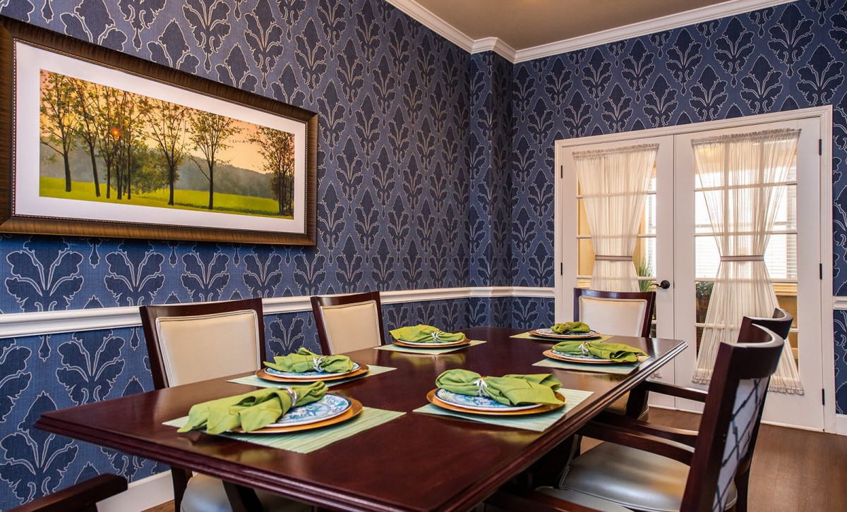 A beautifully decorated dining room with elegant blue wallpaper and a well-set dinner table.