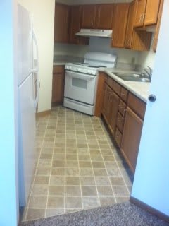 A small kitchen featuring a stove, refrigerator, and wooden cabinets.