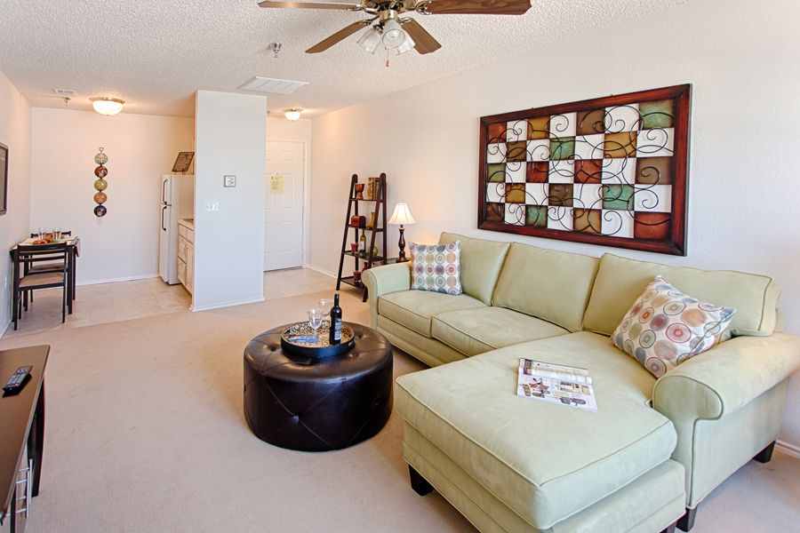 A cozy living room with a light green sofa, a round coffee table, and colorful artwork on the wall.