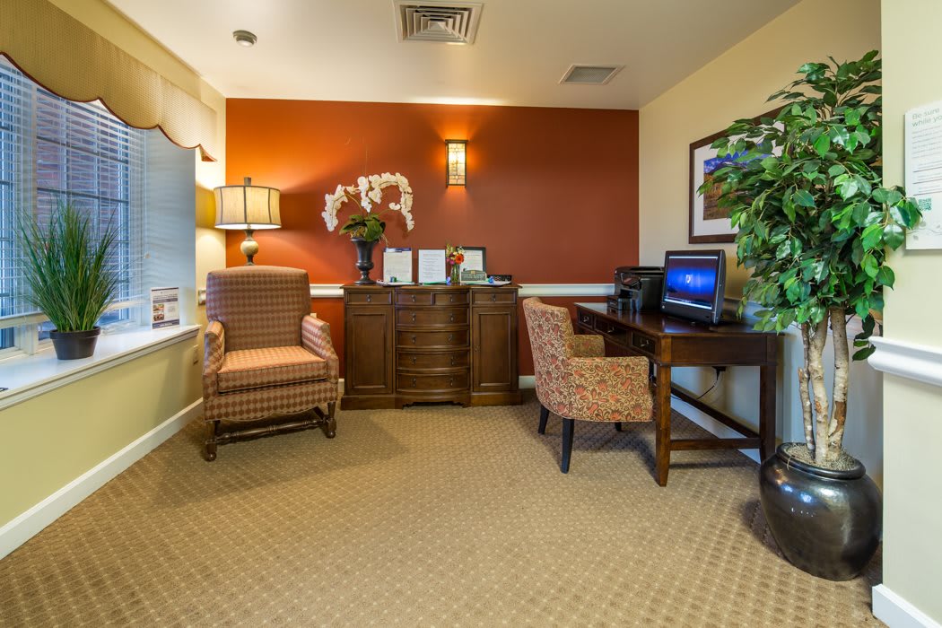 A cozy office area featuring comfortable chairs, a computer desk, and decorative elements.