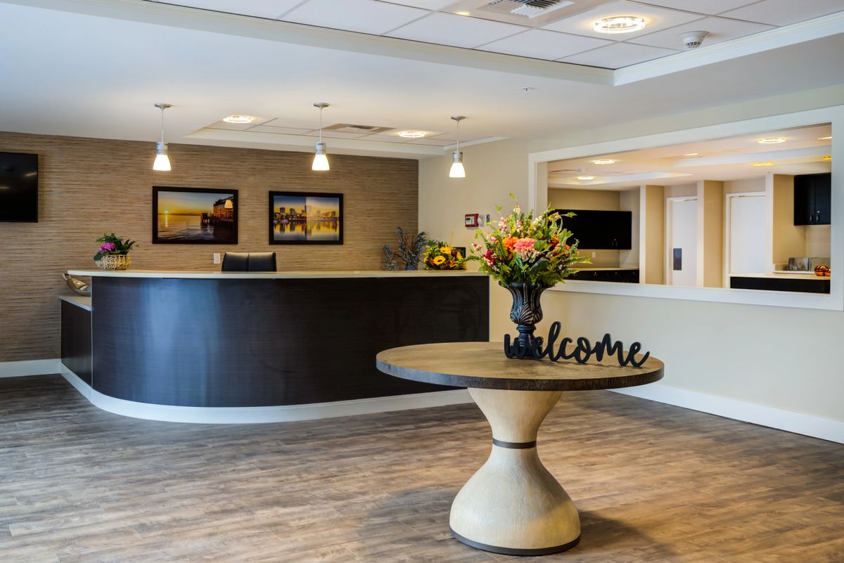 A modern lobby reception area featuring a welcome sign and floral arrangement.
