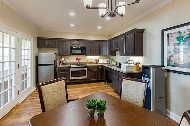 A modern kitchen with dark wooden cabinets, stainless steel appliances, and a cozy dining area.