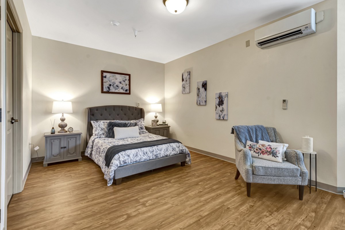 A cozy, well-decorated bedroom featuring a bed with upholstered headboard, side tables with lamps, and wall art.