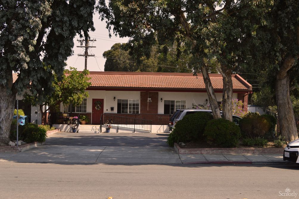 A one-story brick building with trees and a parked car in front.