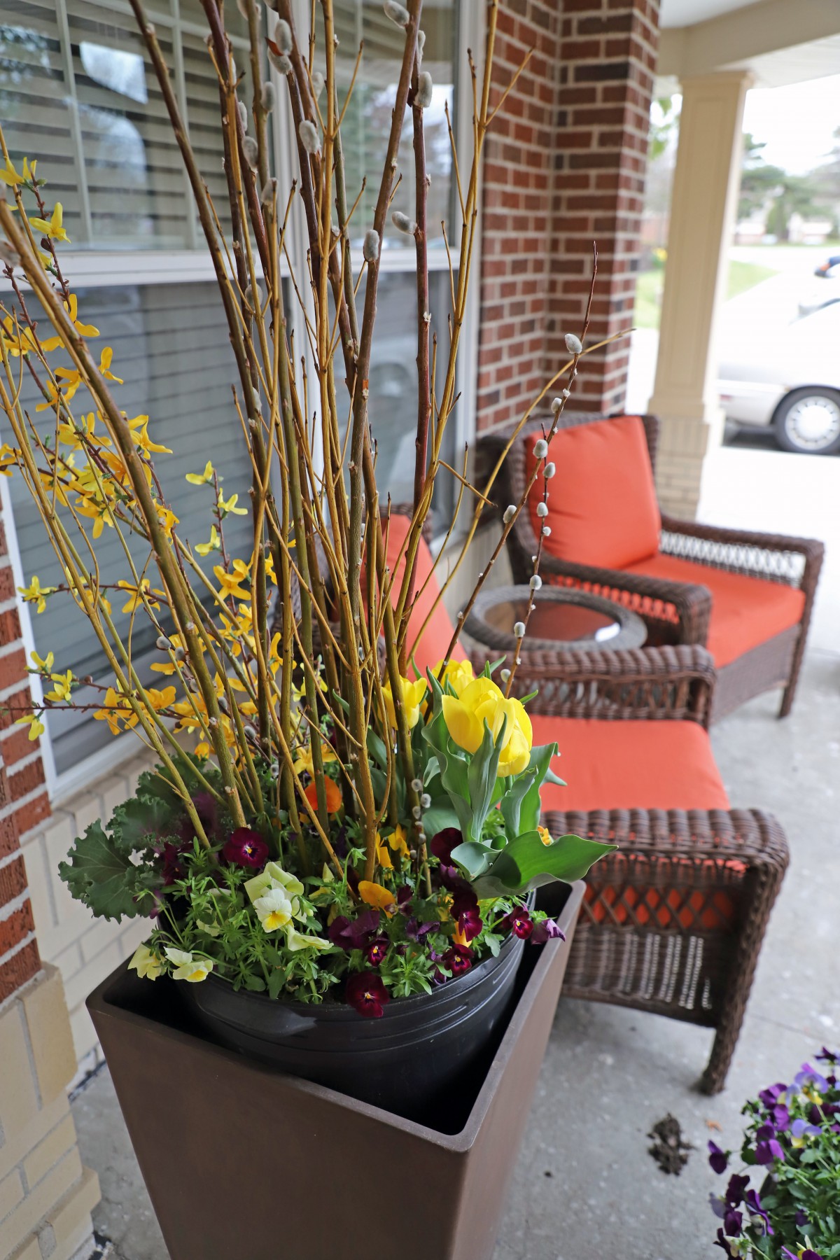 A cozy porch with wicker chairs and a vibrant flower arrangement in a planter.