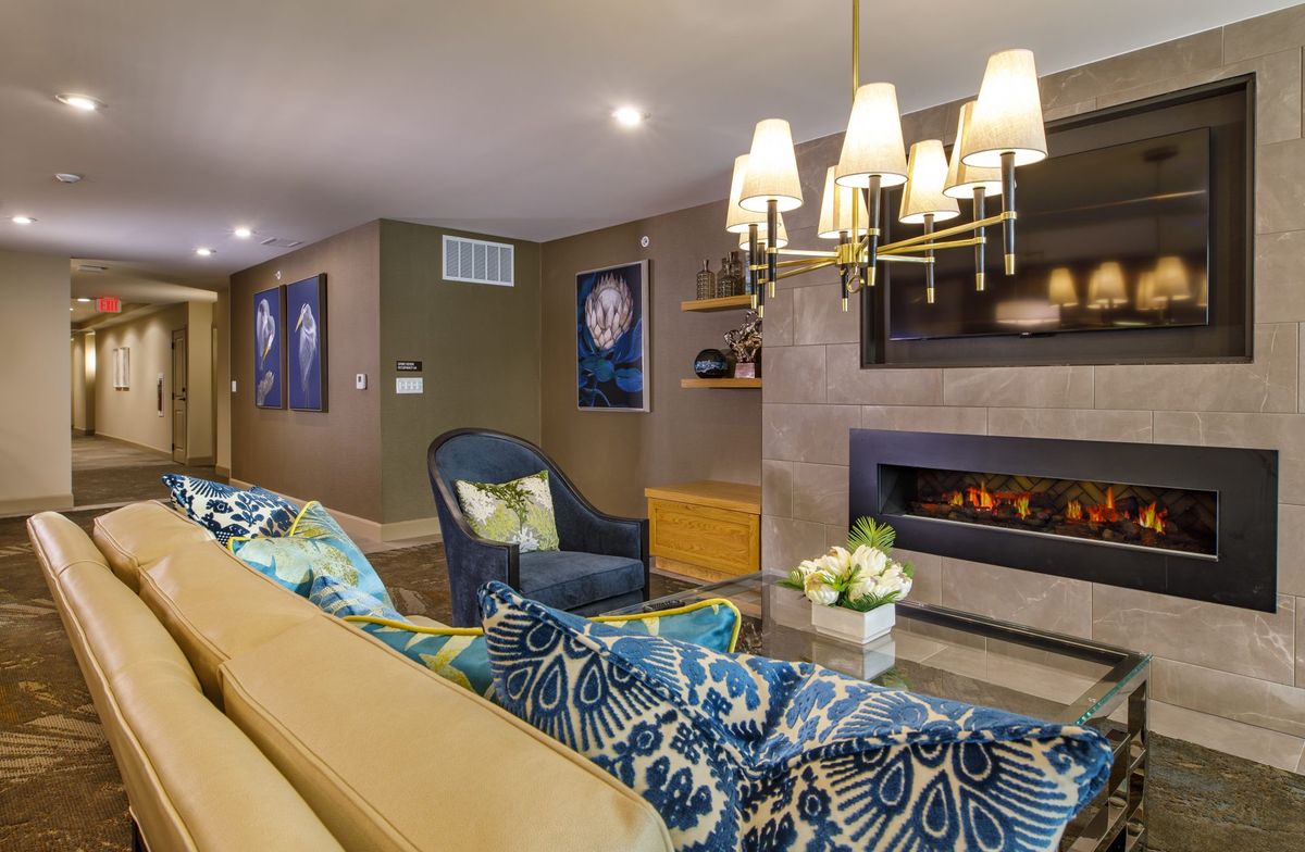 A stylish living room featuring a modern fireplace, elegant chandelier, and colorful decor.