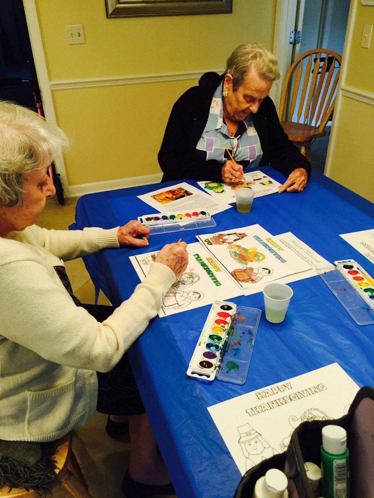 Seniors engaging in a watercolor painting activity at a table.