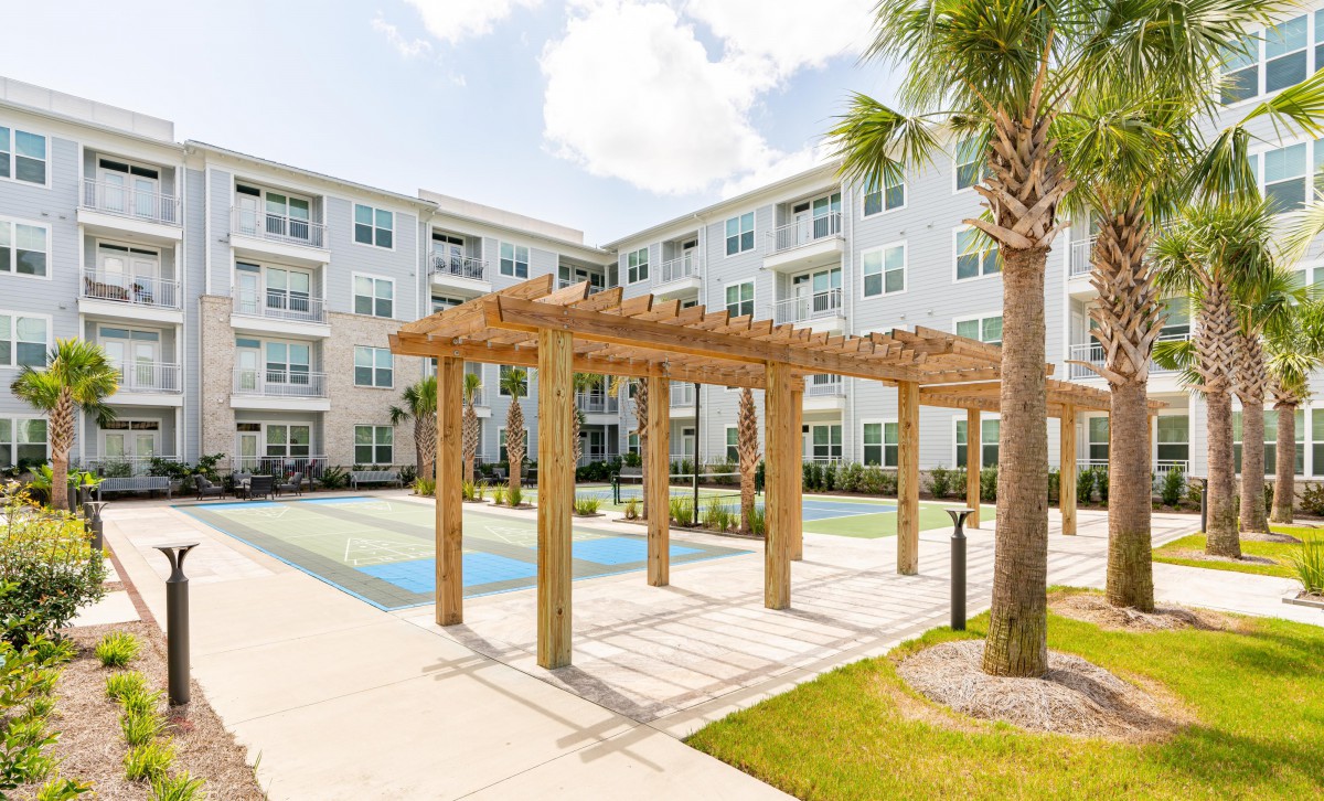 A modern apartment complex featuring a pergola and pool area surrounded by landscaped greenery.