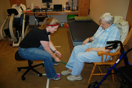 A therapist assists an elderly patient with an exercise or activity during a rehabilitation session.
