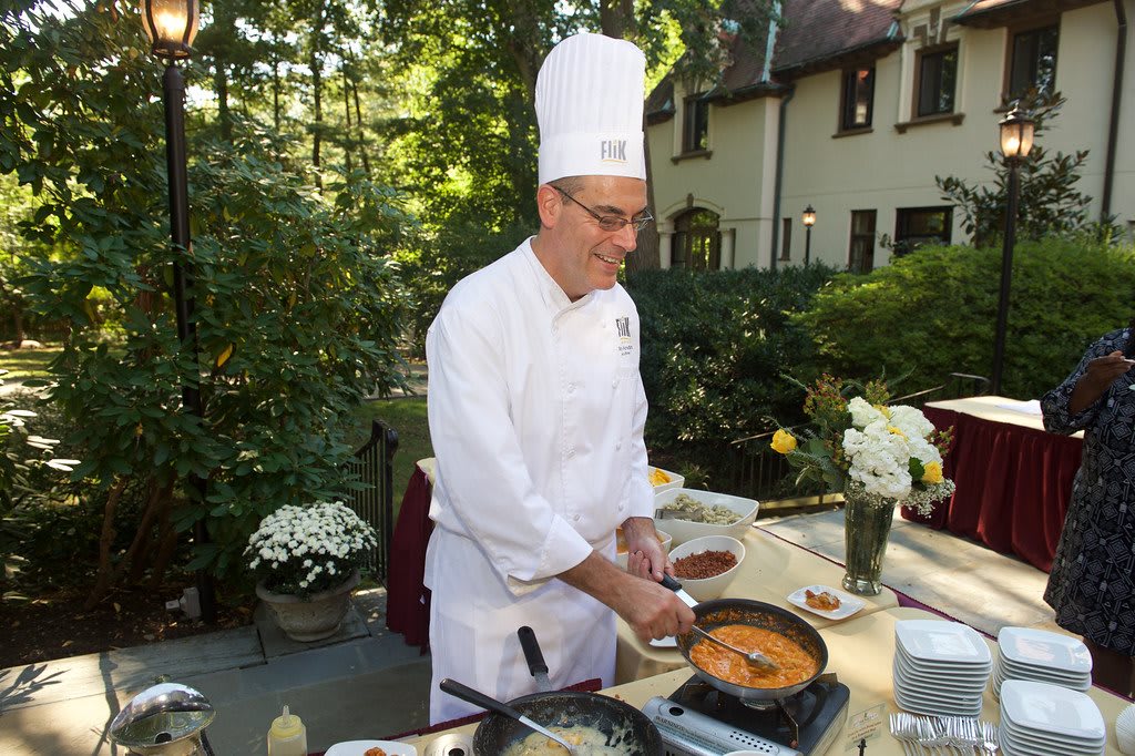 A chef cooking outdoors in a garden setting.