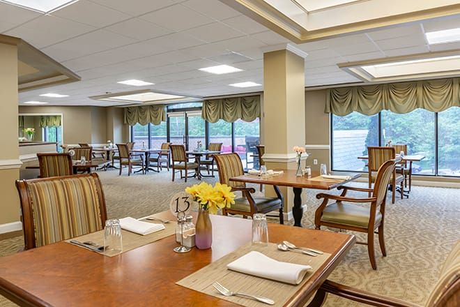 A spacious dining room with elegantly set tables and comfortable seating, featuring large windows and modern decor.