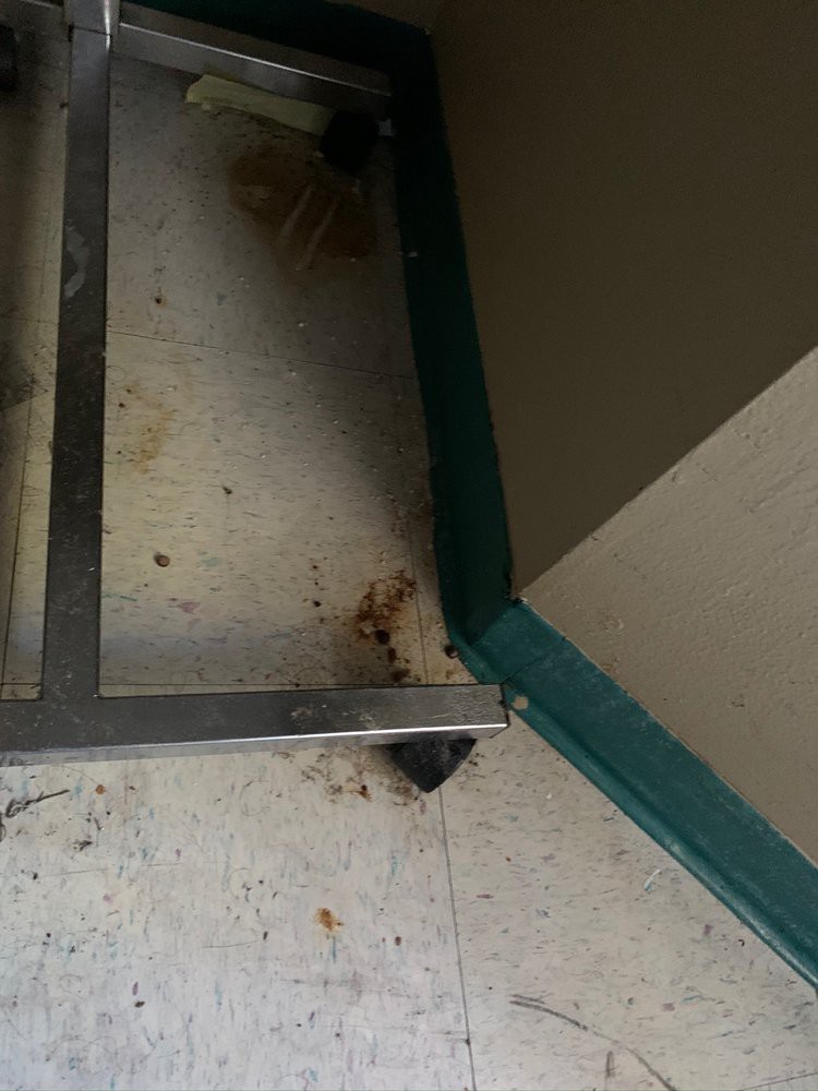 A dirty corner of a room with grime and a mop in the background.