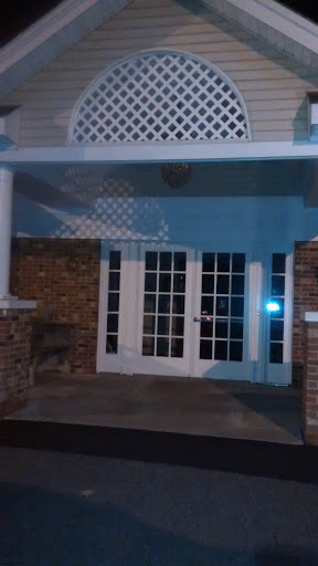 A view of a building's entrance at night, featuring glass doors and soft lighting.
