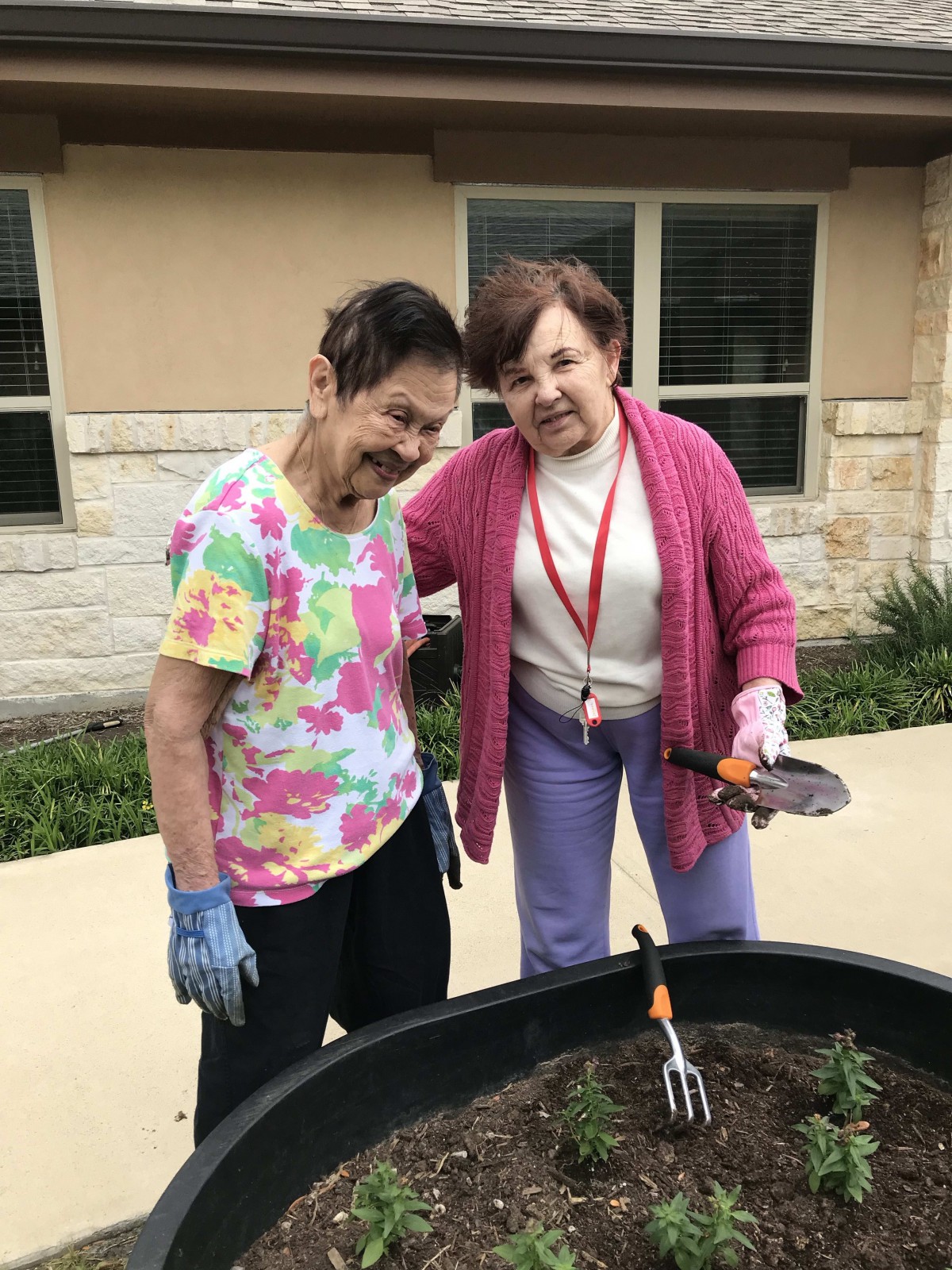 Two elderly women enjoying a gardening activity together outside.