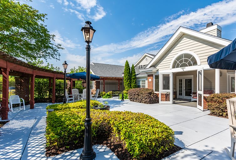 A well-maintained outdoor patio area featuring landscaped gardens, a modern building, and clear blue skies.