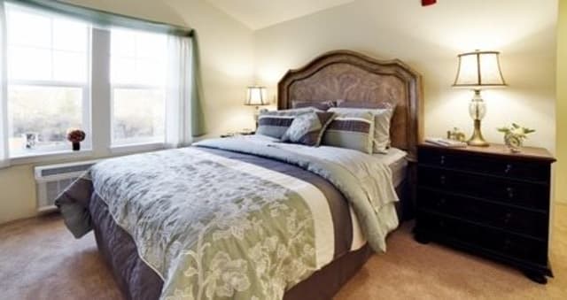 A cozy and well-decorated bedroom with a classic wooden headboard and elegant bedding.
