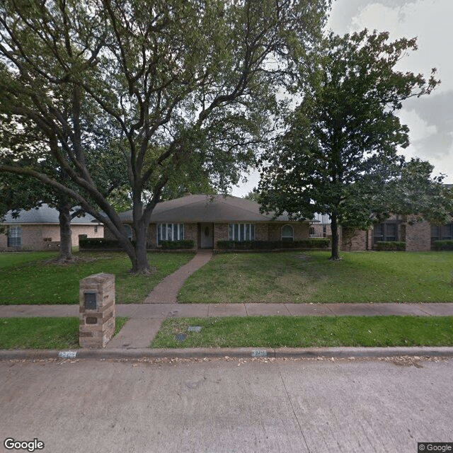 A suburban house with a large front yard and trees.