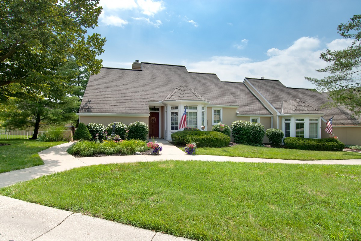A suburban house with a well-maintained lawn and landscaping under a clear, sunny sky.