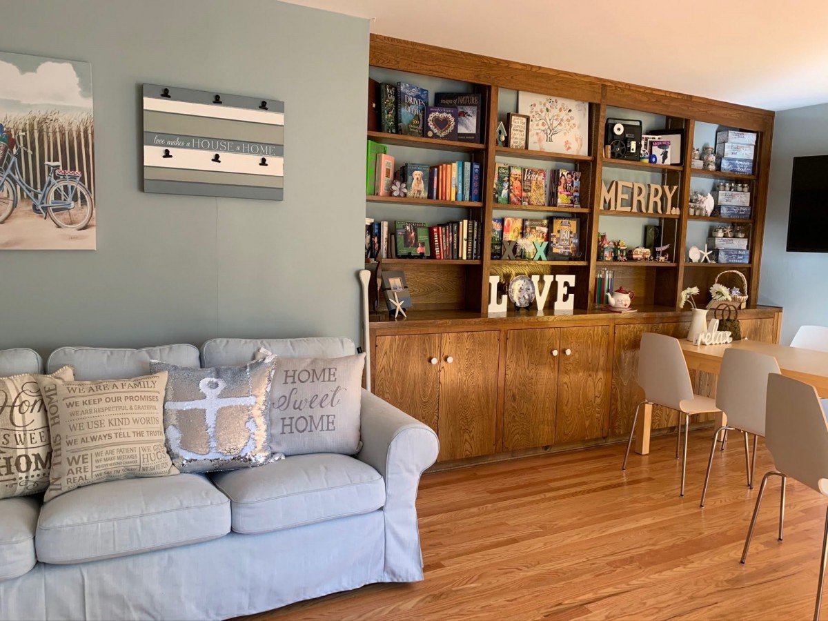 A cozy living room with a light blue sofa, decorative cushions, and bookshelves filled with various items.