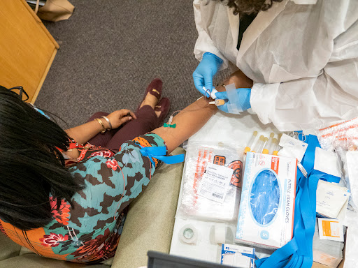 A healthcare professional prepares to take a blood sample from a patient in a clinical setting.