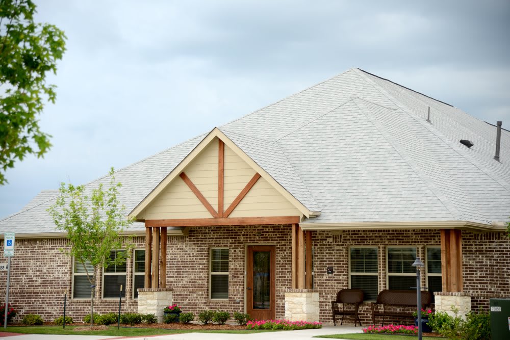 A modern brick house with a large roof and inviting front porch.