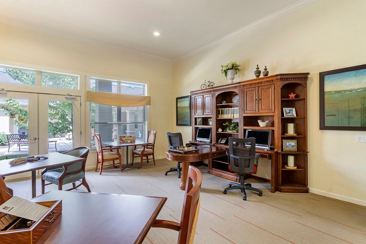A spacious home office with multiple workstations, bookshelves, and large windows allowing ample natural light.