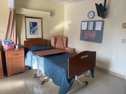 A hospital room featuring a bed, armchair, and wall decor.