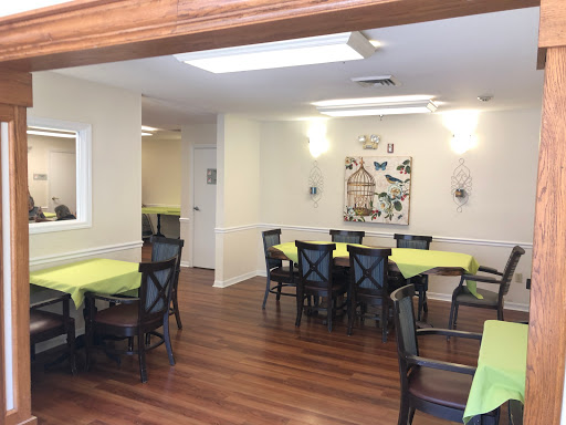 A bright and inviting dining area with green tablecloths and wooden flooring.
