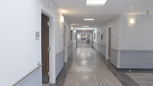 A well-lit hospital corridor with doors leading to various rooms.