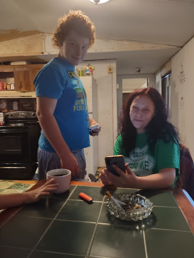 A casual moment shared between friends at the kitchen table, engrossed in their phones.