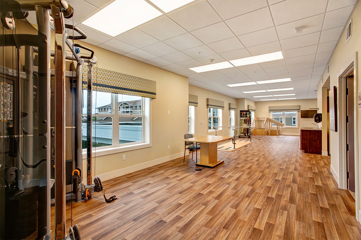 A spacious and well-lit fitness center with modern exercise equipment and wood flooring.